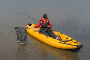 Kayak fishing at lake. Fisherwoman with pike fish on inflatable boat with