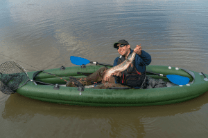 Kayak fishing. Fisherman caught pike fish on inflatable boat with fishing
