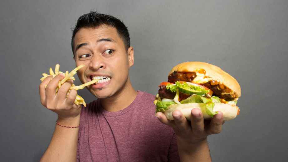 a man eating fries and a burger