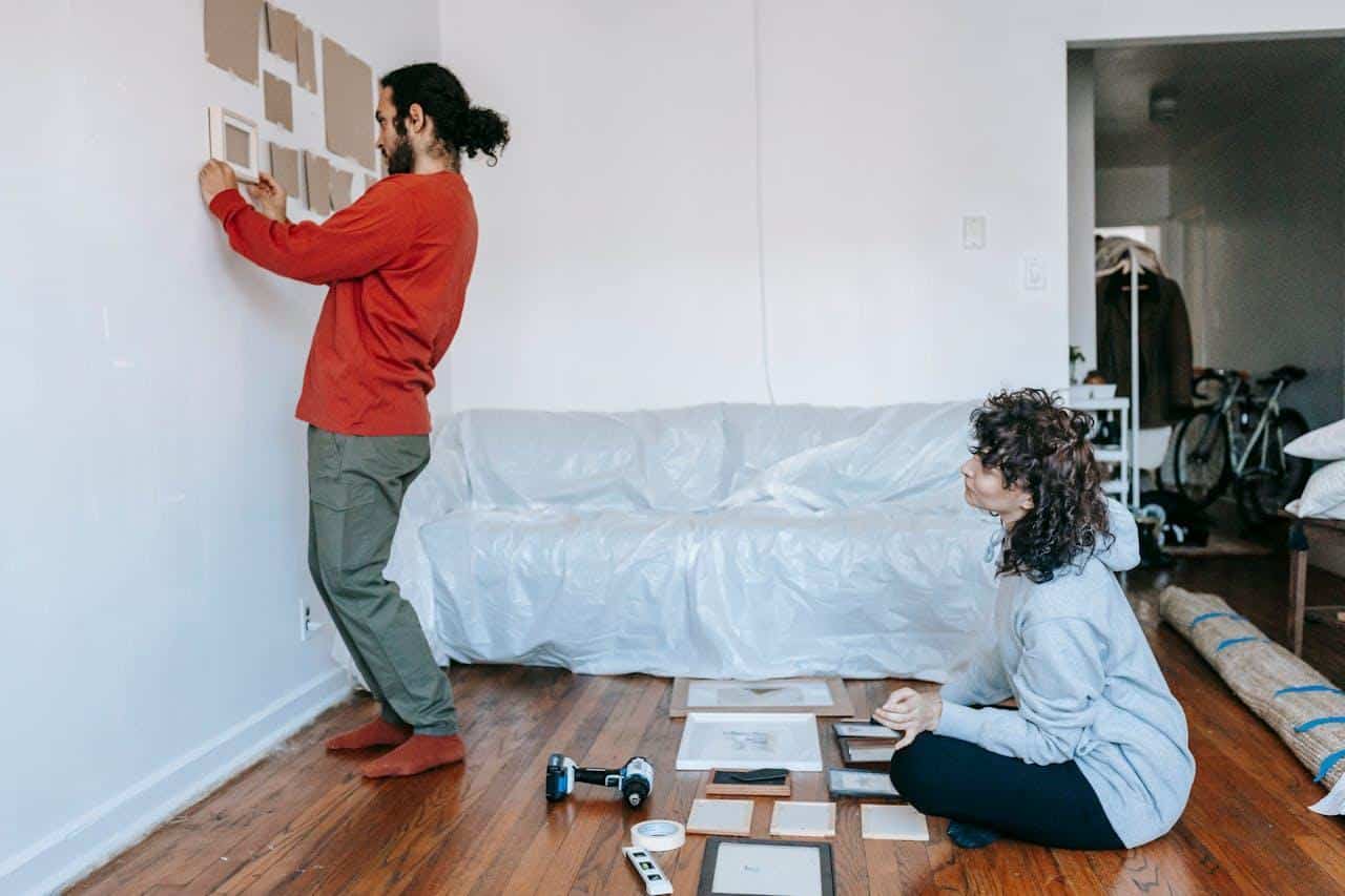 A couple making a picture wall in a new home.